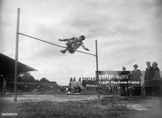 Athlète suisse Eggenberg sautant en hauteur devant le ministre des Sports Monsieur Lafont, au stade de Colombes, France en 1935.