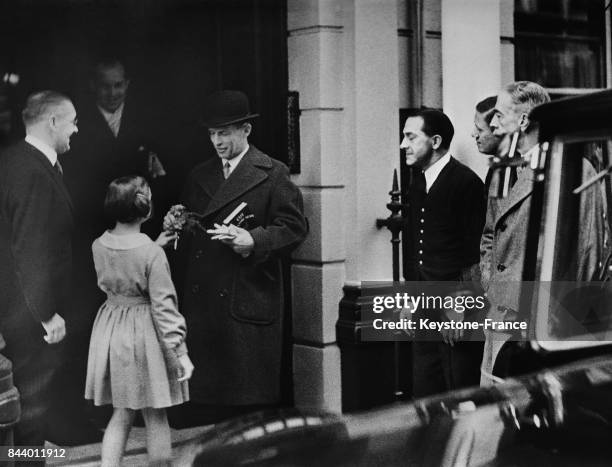 Au moment où le roi Georges quitte son domicile pour se rendre à la gare, une petite fille l'accoste et lui offre un bouquet de fleurs, à Londres,...