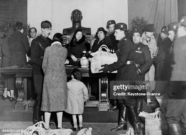 Madame Mussolini, au centre, sous le buste de son époux, préside la distribution de vivres à la Villa Torlonia à Rome, Italie le 24 décembre 1935.