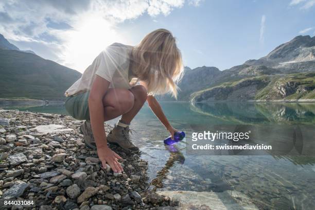botella de relleno rubia de senderismo de lago de montaña - turismo ecológico fotografías e imágenes de stock