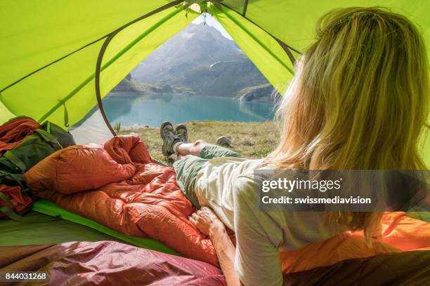 young woman relaxing in tent at sunset - bivouac stock pictures, royalty-free photos & images