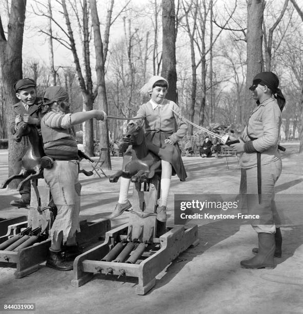 Dans le Jardin des Tuileries, une fille sur son cheval mécanique est attaquée par deux corsaires, à Paris, France le 8 mars 1956.