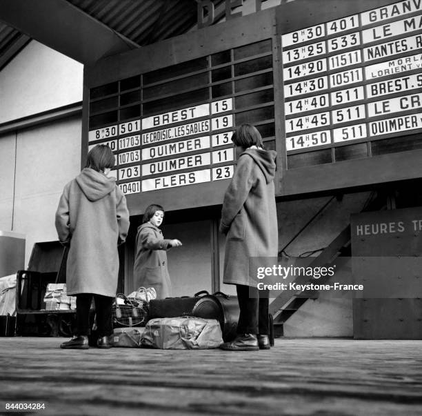 La Gare Montparnasse, des enfants regardent le panneau d'affichage de départ des trains, à Paris, France le 29 mars 1956.