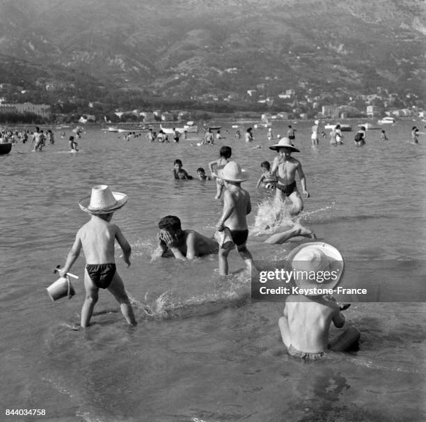 Enfants jouant dans la mer, lors des vacances, à Menton, France, en 1956.