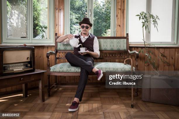 uomo vintage che beve tè - antique sofa styles foto e immagini stock