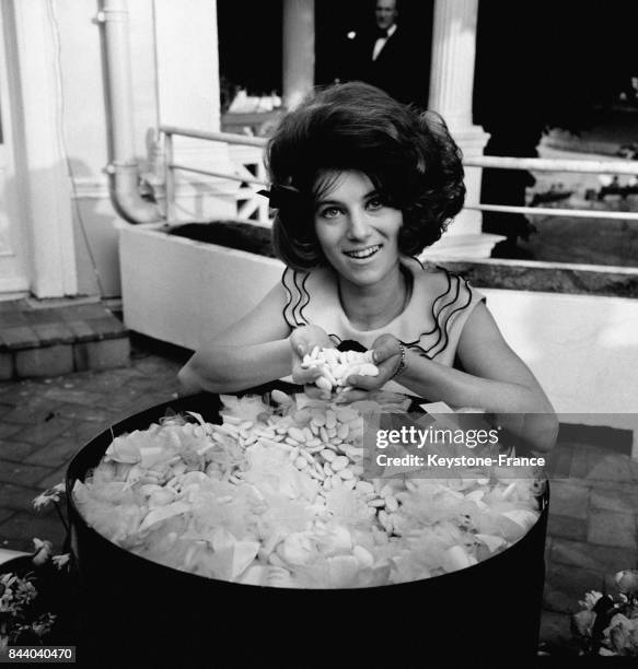 La chanteuse Sheila posant devant une bassine de dragés pour le baptême d'une nouvelle crème de beauté, à Paris, France le 22 mai 1964.