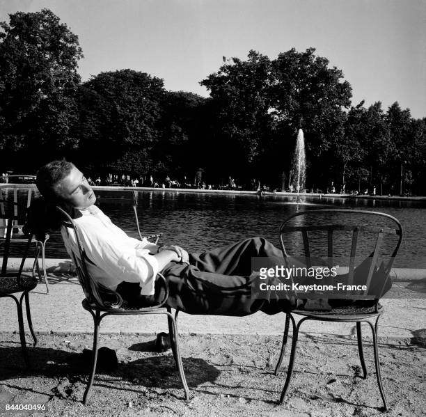 Autour du bassin du Jardin des Tuileries, un Parisien se repose en prenant le soleil, à Paris, France le 11 juin 1964.