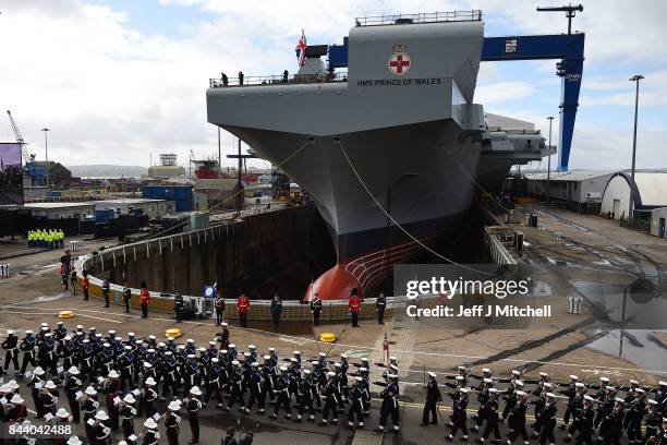 Royal Navy servicemen march past HMS Prince of Wales before a naming ceremony for the aircraft carrier at Rosyth Dockyard on September 8, 2017 in...