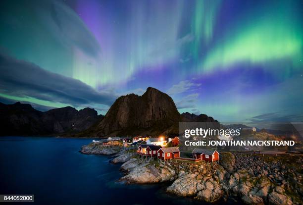 Northern lights illuminate the sky over Reinfjorden in Reine, on Lofoten Islands, Arctic Circle, on September 8, 2017.