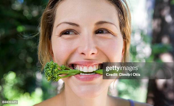 woman biting into broccoli - brocoli 個照片及圖片檔