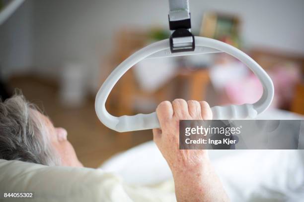 Eberswalde-Finow, GERMANY A resident lying in bed holds on to handle in a retirement home on August 08, 2017 in Eberswalde-Finow, Germany.