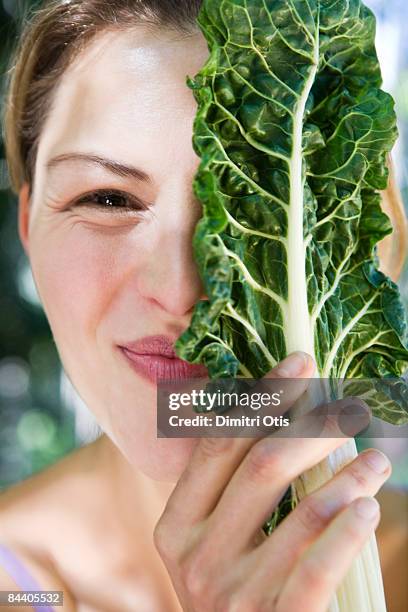 woman covering half her face with spinach - spinach stock pictures, royalty-free photos & images