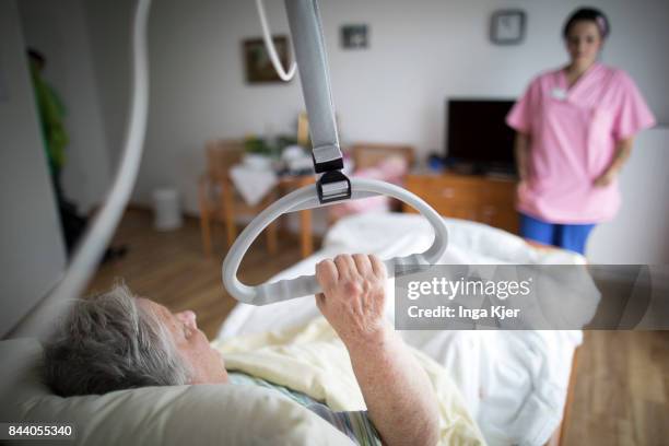 Eberswalde-Finow, GERMANY A resident lying in bed holds on to handle in a retirement home on August 08, 2017 in Eberswalde-Finow, Germany.