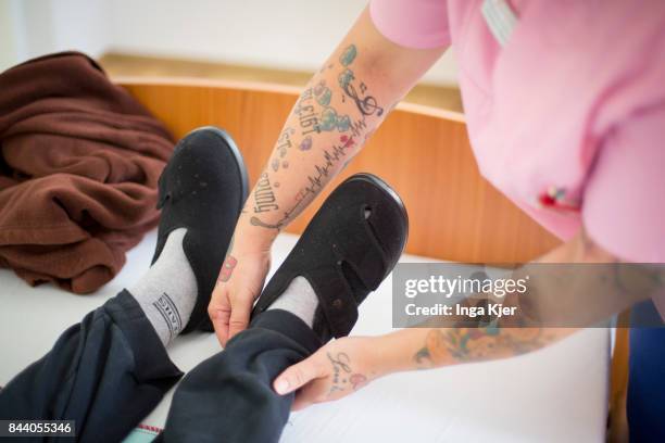Eberswalde-Finow, GERMANY A geriatric nurse puts a resident shoes on on August 08, 2017 in Eberswalde-Finow, Germany.