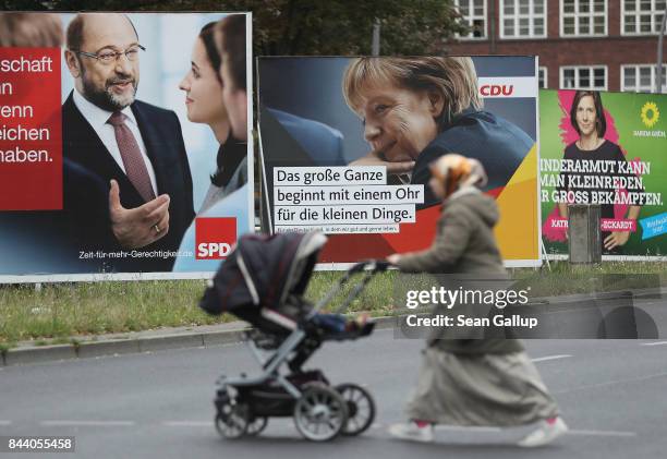 Muslim woman pushes a pram past election campaign billboards that show German Social Democrat chancellor candidate Martin Schulz , German Chancellor...