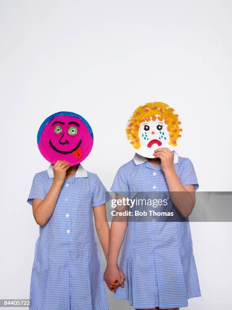 School girls hide their faces behind painted paper plates