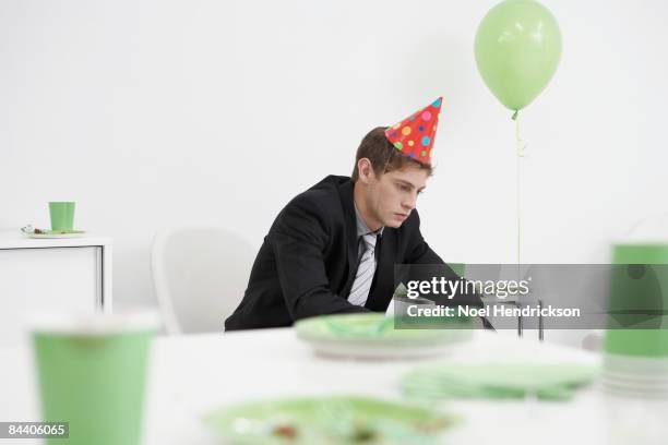 businessman wearing party hat looking serious - messy table after party 個照片及圖片檔