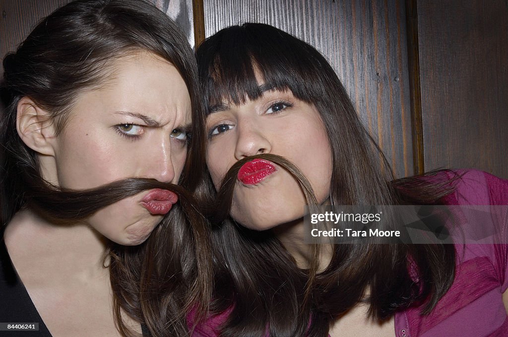 Two women using hair as moustaches