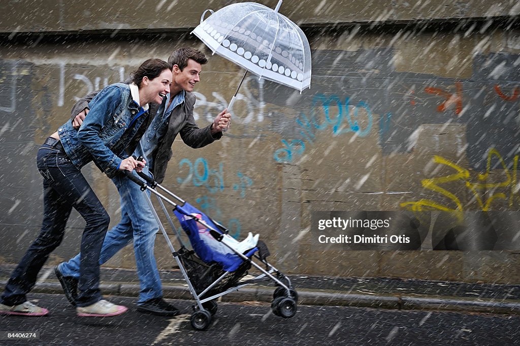 Couple pusing a pram in the rain