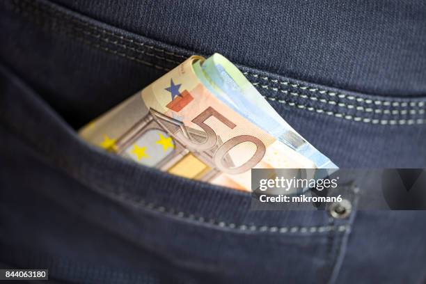 wad of cash into the pocket of jeans - phone in back pocket stock pictures, royalty-free photos & images