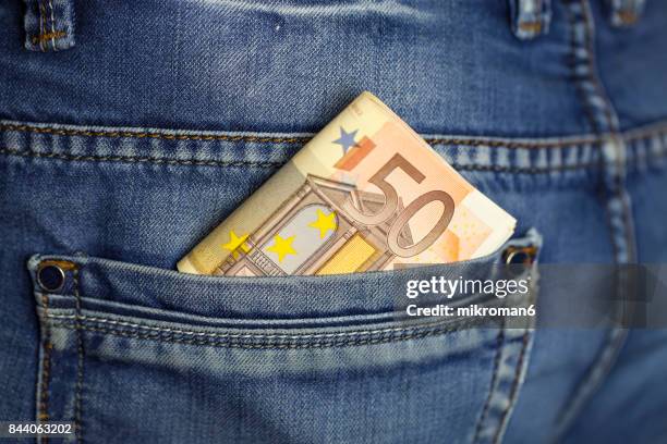 wad of cash into the pocket of jeans - fajo de billetes de euro fotografías e imágenes de stock