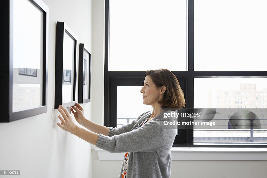  Woman adjusting picture frame at home