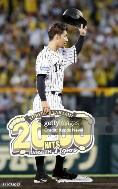 Takashi Toritani of the Hanshin Tigers acknowledges the crowd after picking up his 2,000th career hit in the second inning against the DeNA BayStars...