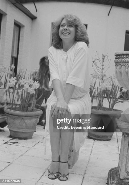 English singer and actress Elaine Paige sits on a stool in a backyard, UK, 6th April 1978.