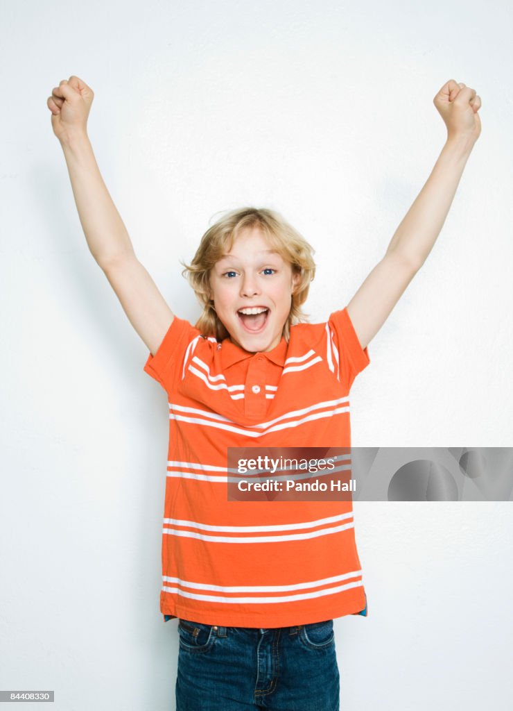 Boy (10-11) cheering, arms up, smiling