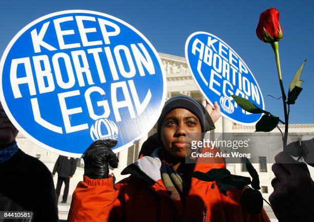 Local pro-choice activist Lisa King holds a sign in front of the US Supreme Court as a pro-life activist holds a rose nearby during the annual "March...