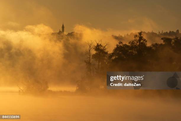 early morning fog on lake ammersee with andechs monastery in the distance, upper bavaria, germany - dießen stock-fotos und bilder
