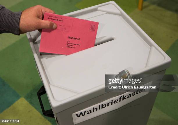Federal election 2017. Symbol photo on the topic postal vote, election, elect, ballot paper, etc. Throwing of a postal ballot envelope into a ballot...