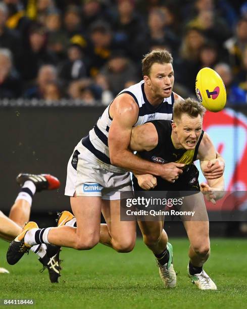 Jack Riewoldt of the Tigers handballs whilst being tackled by Lachie Henderson of the Cats during the AFL Second Qualifying Final Match between the...