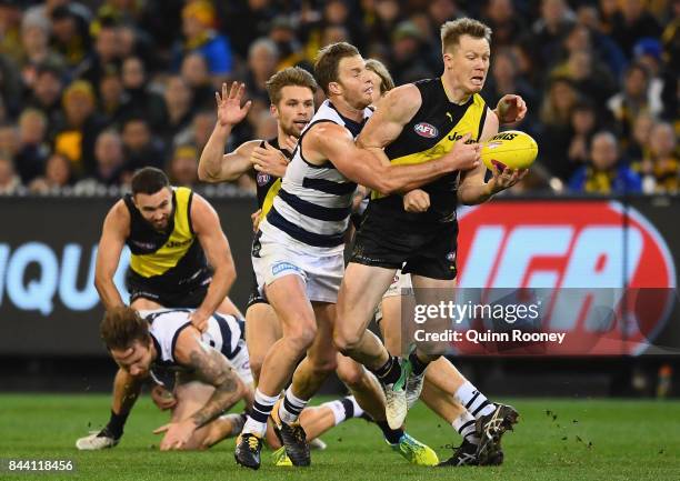 Jack Riewoldt of the Tigers handballs whilst being tackled by Lachie Henderson of the Cats during the AFL Second Qualifying Final Match between the...