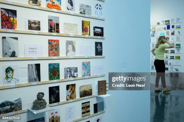 Woman looks at some of the postcards displayed in the RCA Secret Postcard fundraising exhibition at the Royal College of Art on September 8, 2017 in...