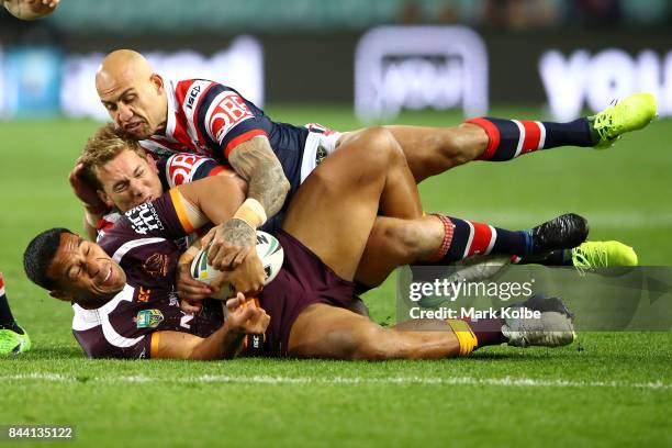 Tautau Moga of the Broncos is tackled by Mitchell Aubusson and Blake Ferguson of the Roosters during the NRL Qualifying Final match between the...