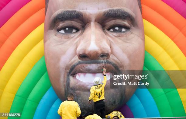 People clean a giant inflatable face of Kanye West at the Bestival festival being held at the Lulworth Estate on September 8, 2017 in Dorset,...