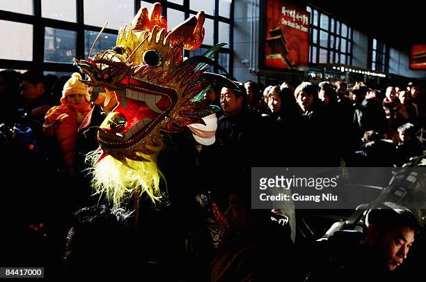 Passenger holds a dragon model as he waits to board a train at Beijing West Railway Station on January 23, 2009 in Beijing, China. Millions of...