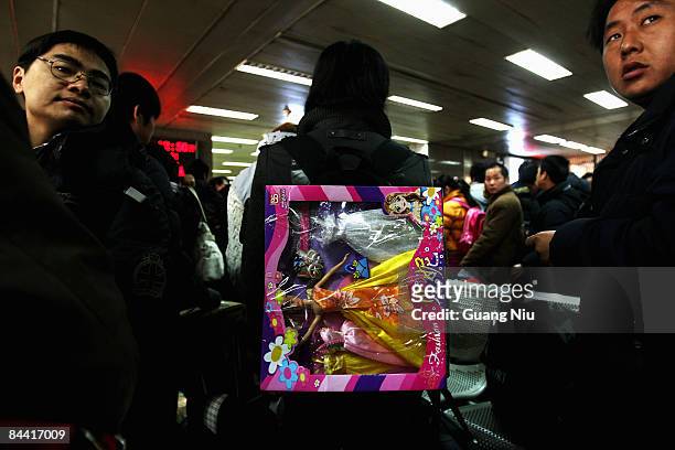Man carries a fashion toy as he waits to board a train at Beijing West Railway Station on January 23, 2009 in Beijing, China. Millions of Chinese...