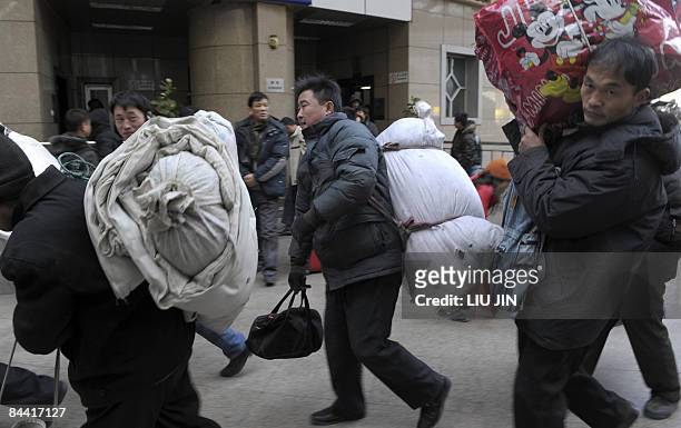 Passengers carry their luggages outside the Beijing West Railway Station in Beijing on January 23, 2008. The Lunar New Year falls this year on...