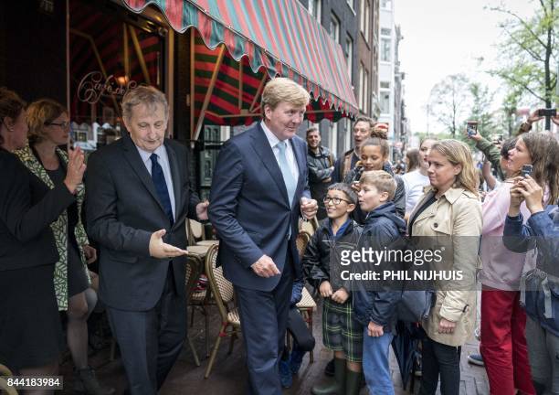 Dutch King Willem-Alexander leaves a cafe following by Amsterdam's mayor Eberhard van der Laan , as he visits the Amsterdam neighborhood the...