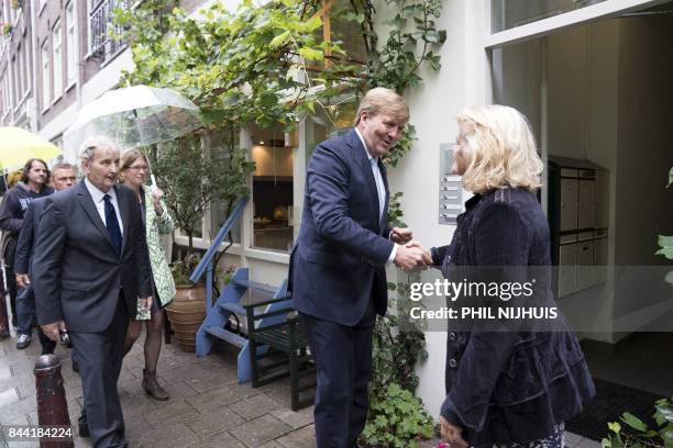 Dutch King Willem-Alexander shakes hands with a resident, as he visits the Amsterdam neighborhood the "Jordaan" flanked by Amsterdam's mayor Eberhard...