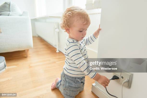 baby boy touching electrical plug in the wall. - electrical safety stock pictures, royalty-free photos & images