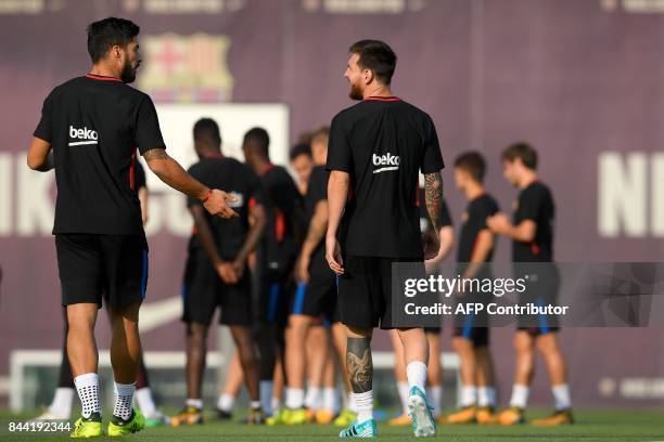 Barcelona's Uruguayan forward Luis Suarez chats with Barcelona's Argentinian forward Lionel Messi during a training session at the Sports Center FC...