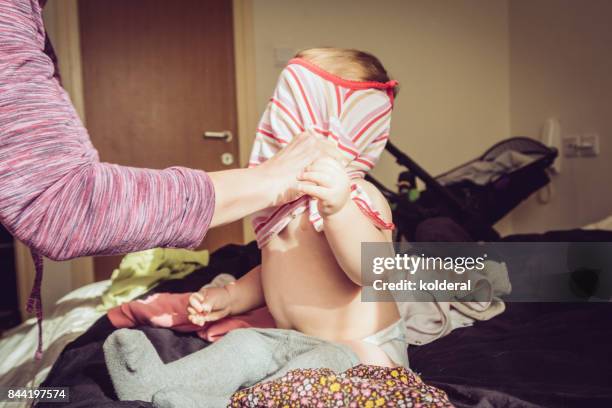 mother dressing baby girl in the bedroom early morning - kids dressing up stock-fotos und bilder