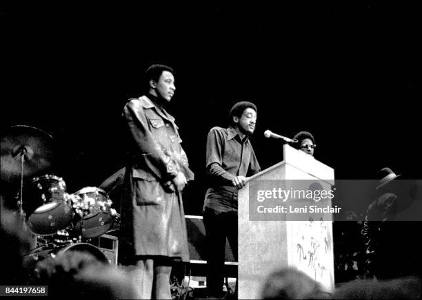 Black Panther Party Leader Bobby Seale speaking at podium on stage at the John Sinclair Freedom Rally at the Crisler Arena, surrounded by bodyguards,...