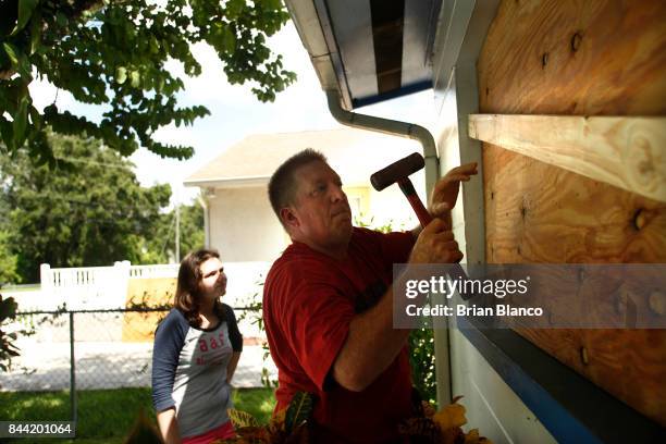 With his niece Lanae Corley looking on, Kurt Vetter works to install plywood over his home's windows as residents prepare their homes ahead of...