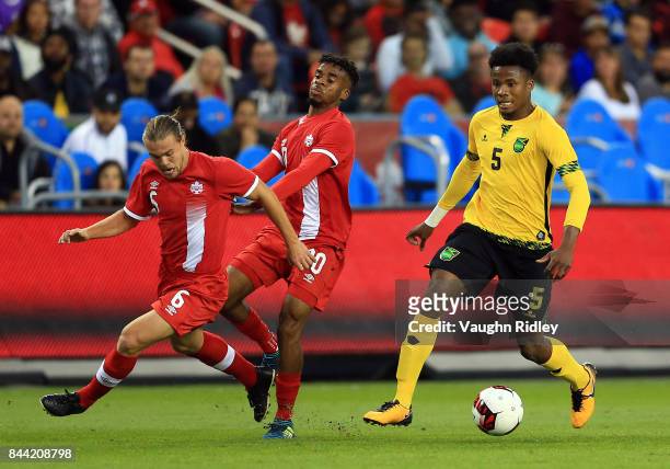 Samuel Piette and Raheem Edwards of Canada battle for the ball with Alvas Powell of Jamaica during an International Friendly match at BMO Field on...