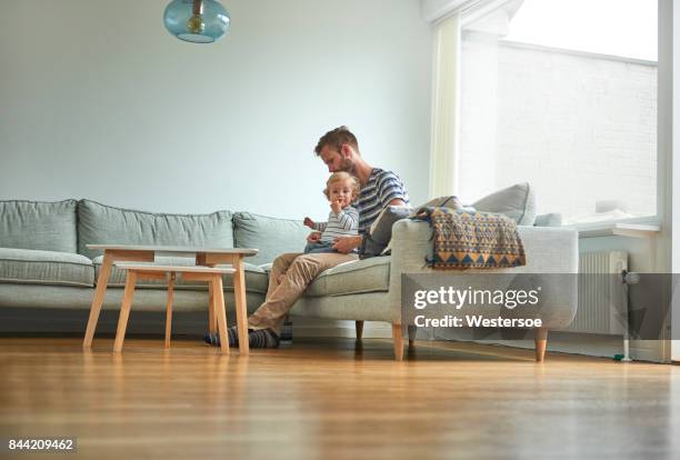 father and son on couch. putting on clothes - low angle view home stock pictures, royalty-free photos & images
