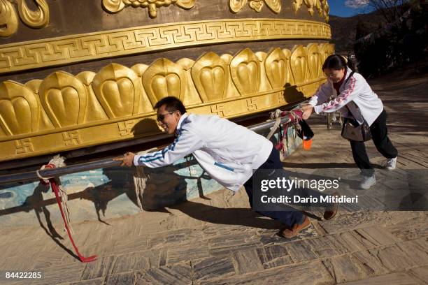 Tourists spinning a prayer wheel, specially built as part of the tourism incentive, in the town of Zhongdian, Yunnan Province, China. Zhongdian was...